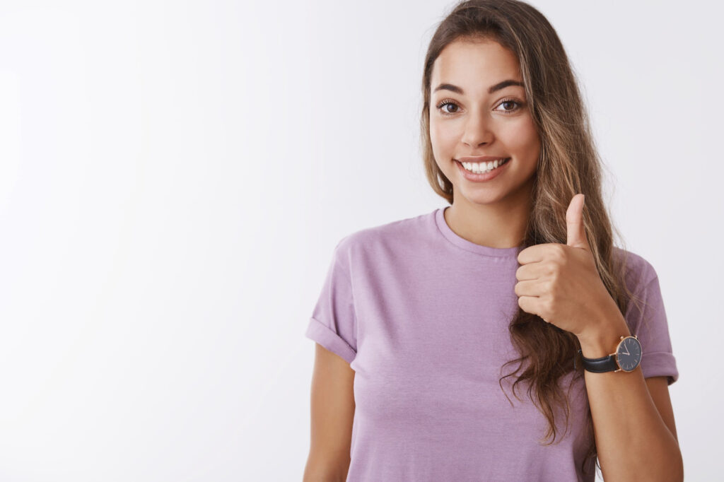 a woman giving a thumbs up after having cosmetic dental work